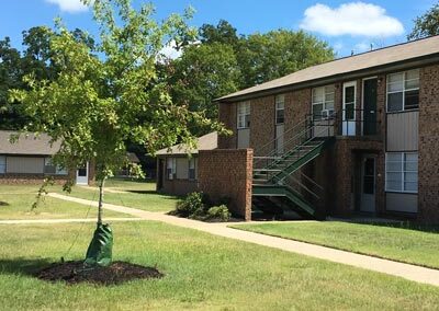 brick exterior of apartment building with green grass and tree